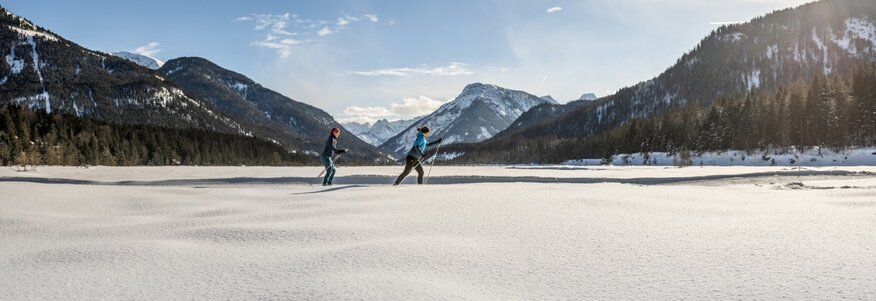 Hier sehen Sie Personen beim Skilanglaufen in den Bergen. 